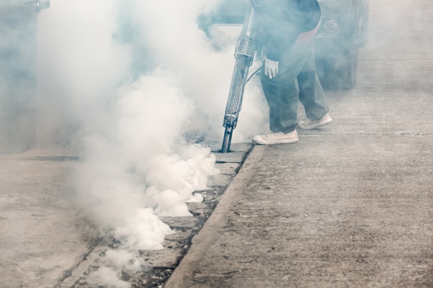 Lavoratore annebbiando lo scarico delle strade con insetticidi per uccidere il terreno fertile della zanzara Aedes, portatore di dengue e virus Zika