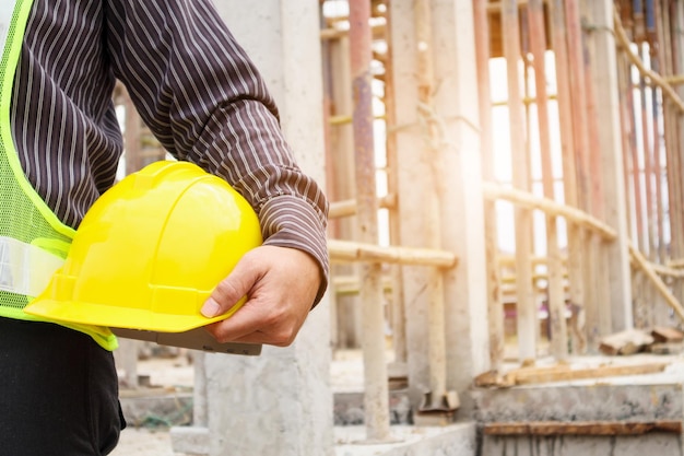 Lavoratore asiatico dell'ingegnere edile dell'uomo di affari con il casco protettivo al cantiere della casa