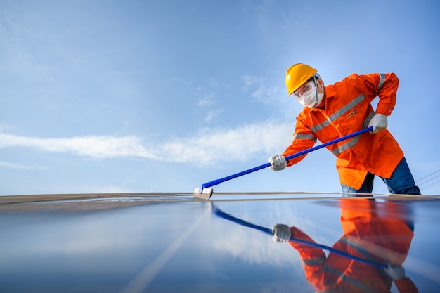 Lavoratore asiatico o ingegnere In una centrale solare Il pannello solare viene pulito utilizzando una scopa per pulirlo. Alla centrale solare.