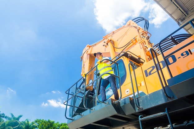 Lavoratore asiatico sul cantiere dell&#39;escavatore della pala