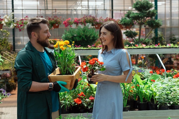 Lavoratore che aiuta il cliente femminile con la pianta nel garden center