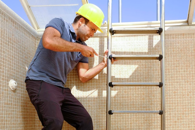 lavoratore che installa una scala per piscina in una piscina vuota