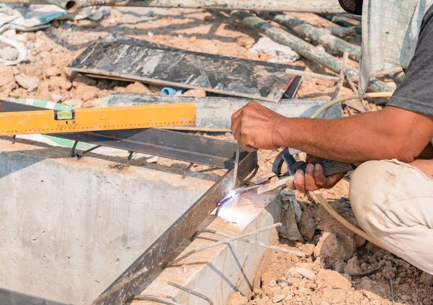 Lavoratore che salda le casseforme sul bordo di un stagno di scarico in un cantiere