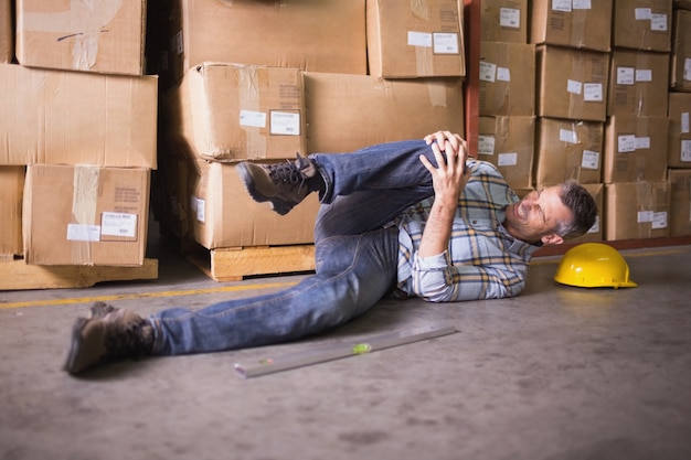 Lavoratore che si trova sul pavimento in magazzino