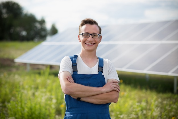 Lavoratore che sta nel campo con solare con i pannelli solari sul backstage.