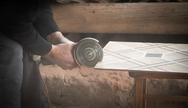 Lavoratore che taglia una piastrella di ceramica con una smerigliatrice