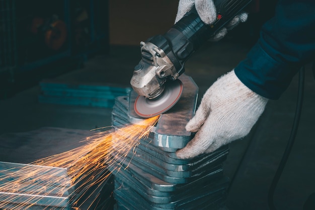 lavoratore che utilizza l&#39;acciaio del macinino nell&#39;officina e ha lanciando scintille.