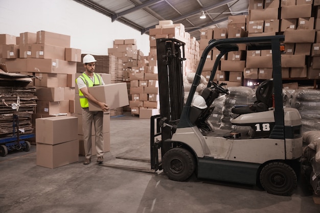 Lavoratore del magazzino che carica su pallet