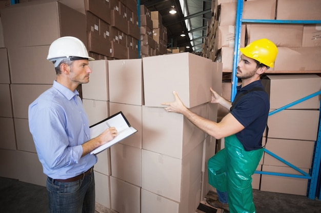 Lavoratore del magazzino che carica su un pallet con il responsabile