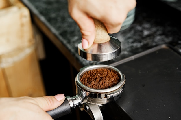 Lavoratore della caffetteria donna che prepara caffè sulla macchina da caffè professionale si chiuda