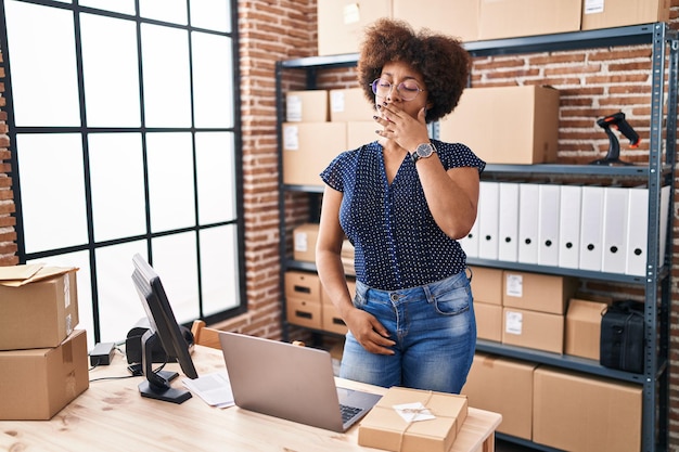 Lavoratore di affari di commercio elettronico della donna dell'afroamericano stanco che sbadiglia all'ufficio