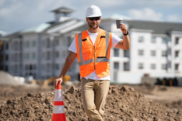 Lavoratore di cantiere con casco che lavora all'aperto un costruttore con un casco di sicurezza durante la costruzione