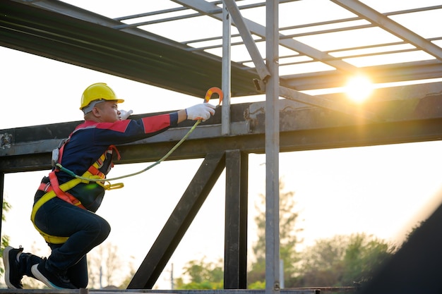 Lavoratore di costruzione asiatico che lavora in altezza Indossa attrezzature di sicurezza e imbracature di sicurezza per lavorare in altezza sul cantiere