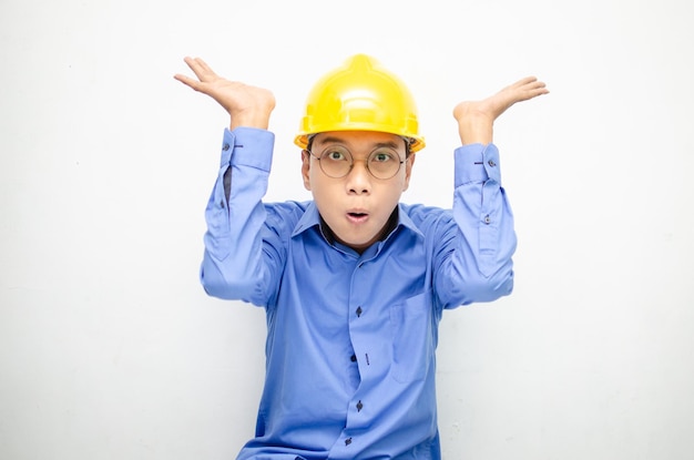 lavoratore di costruzione asiatico in camicia blu e casco di sicurezza giallo che punta il dito e presenta