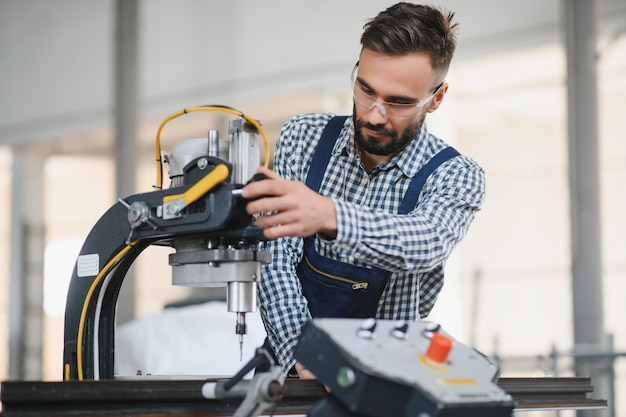 Lavoratore di ingegnere dell'industria pesante professionale felice che indossa uniforme e cappello rigido in una fabbrica di acciaio Specialista industriale sorridente in piedi in una produzione di costruzioni metalliche