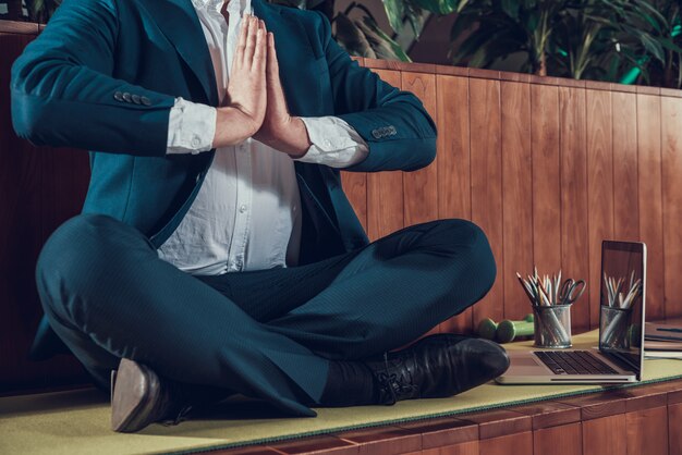 Lavoratore in vestito che medita su banco in ufficio.