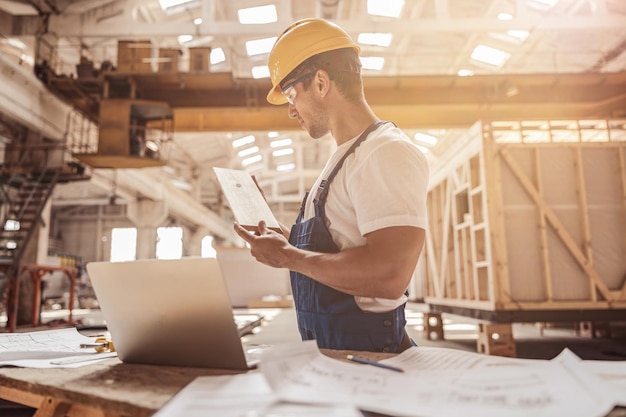 Lavoratore maschio che controlla la tavola di legno al cantiere