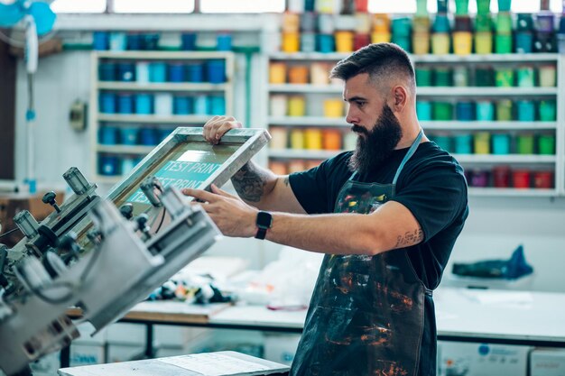 Lavoratore maschio che utilizza una macchina da stampa in un'officina