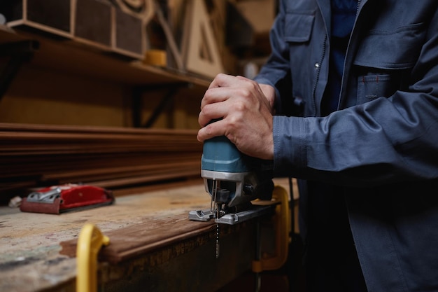 Lavoratore maschio del primo piano che taglia il legno in officina con lo spazio della copia dell'utensile elettrico