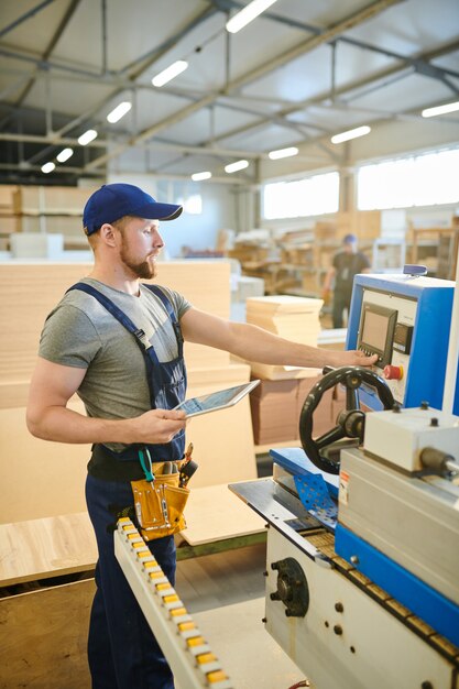 Lavoratore maschio sicuro che per mezzo del computer della macchina della fabbrica