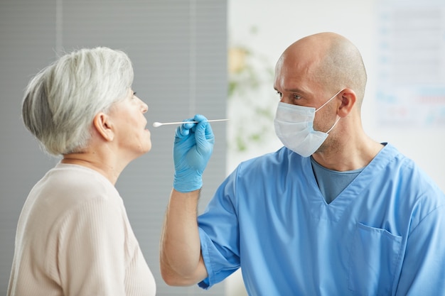 lavoratore medico professionista che prova donna senior che prende il suo tampone faringeo