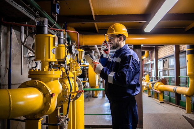 Lavoratore professionista di raffineria in apparecchiature di sicurezza che controllano l'installazione e la pressione del gasdotto