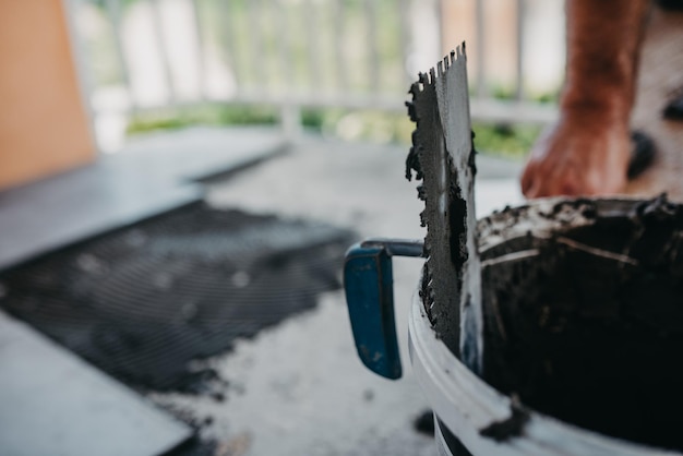 Lavoratore specializzato che installa le piastrelle in ceramica effetto legno sul pavimento Lavoratore che realizza pavimenti in laminato nel cantiere del nuovo appartamento