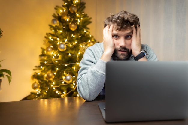 Lavoratore stanco un uomo si siede davanti a un computer portatile la notte di Natale