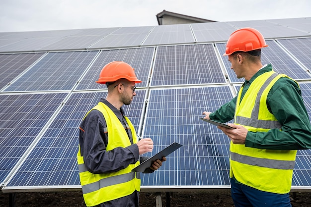 Lavoratori bei giovani ragazzi sani che lavorano all'installazione della costruzione di pannelli solari