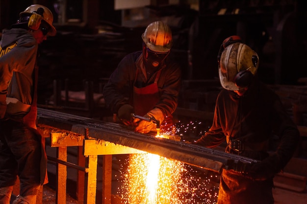 Lavoratori che utilizzano una torcia ad ossigeno e acetilene che tagliano una lastra d'acciaio