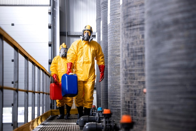 Lavoratori completamente protetti con maschere antigas e guanti in tuta gialla che maneggiano sostanze chimiche pericolose