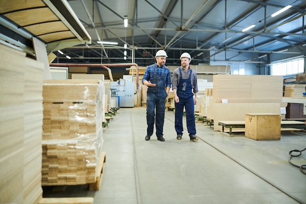 Lavoratori dell'industria che parlano mentre camminando sopra l'officina