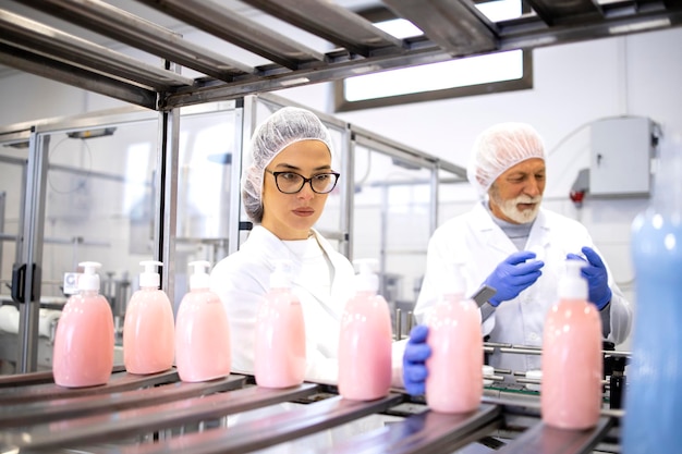 Lavoratori della linea di produzione che controllano la qualità dei cosmetici sulla macchina.