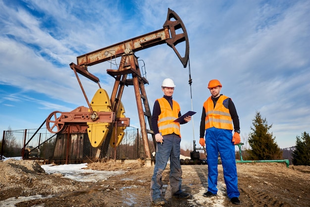 Lavoratori della piattaforma petrolifera in piedi vicino al martinetto della pompa