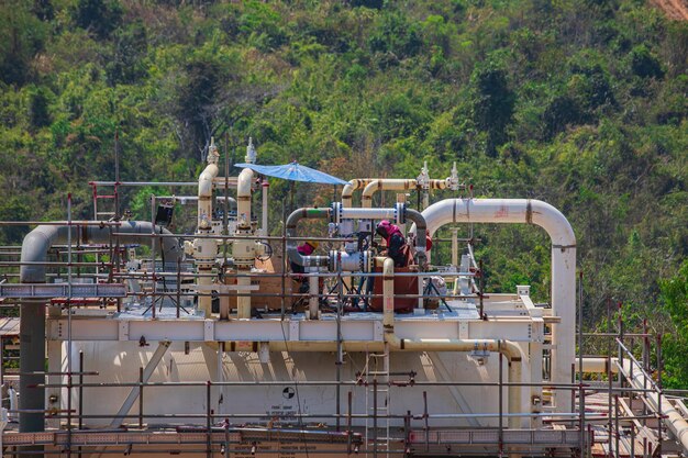 Lavoratori edili che installano scaffolding serbatoio di stoccaggio raffineria di petrolio e impianto e colonna di torre dell'industria petrolchimica