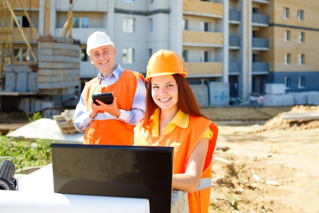 Lavoratori edili femminili e maschii che esaminano laptop e che sorridono