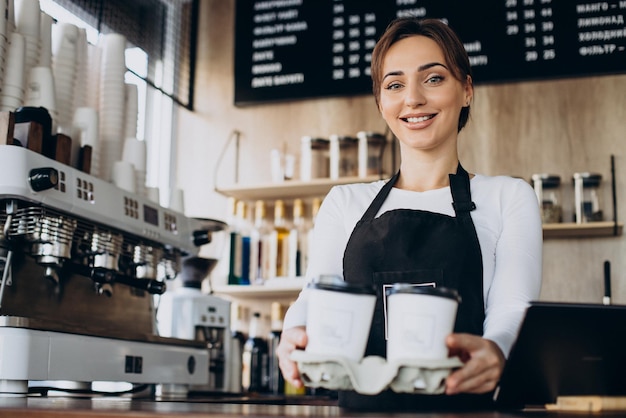 Lavoratrice barista in una caffetteria con in mano una tazza di caffè