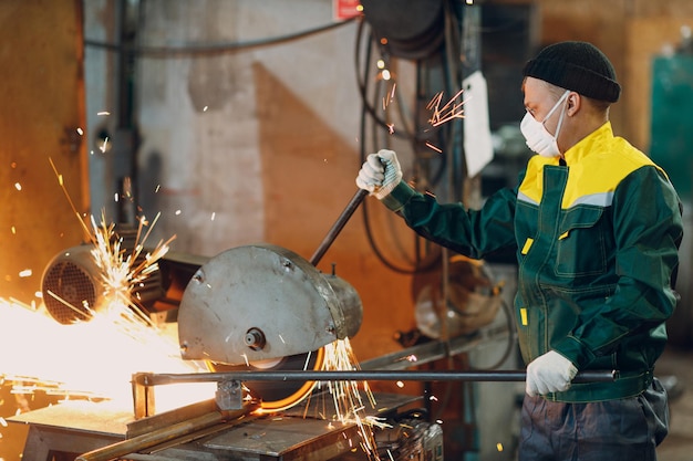 Lavorazione dei metalli con troncatrice grande composta a lama circolare. Scintille nella lavorazione dei metalli in fabbrica