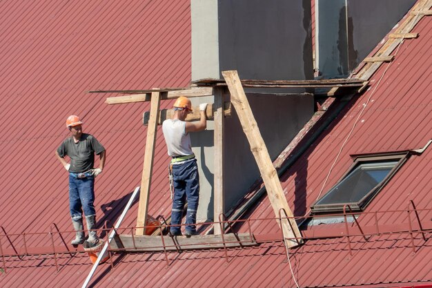 Lavori ad alta quota pericolosi per la vita Una squadra di conciatetti lavora sul tetto senza assicurazione Riparazione del tetto e dei tubi di ventilazione Violazione delle norme di sicurezza