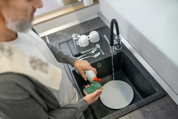 Lavori di casa. Primo piano di un uomo che lava i piatti in cucina