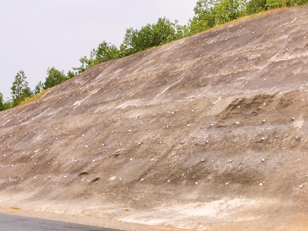 Lavori di consolidamento del pendio collinare lato strada con cemento armato e rete metallica al pr