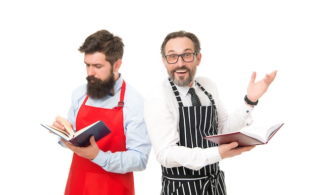 Lavori domestici Cucinare ricette alimentari Come cucinare Uomini hipster con la barba grembiule da cucina leggere libri di cucina Non ho idea di come cucinare il cibo Concetto di libro culinario Uomini responsabili della famiglia Alcuni problemi