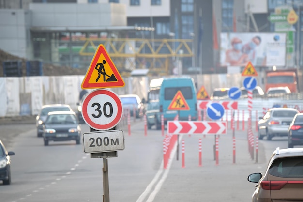 Lavori stradali segnali stradali di avvertimento di lavori di costruzione in una strada cittadina e auto in movimento lento