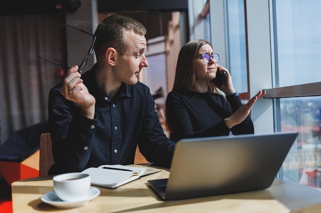 Lavoriamo insieme su un progetto di affari Due giovani colleghi di lavoro lavorano su un laptop in un grande ufficio moderno Partner commerciali in ufficio al lavoro