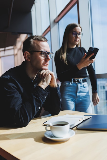 Lavoriamo insieme su un progetto di affari Due giovani colleghi di lavoro lavorano su un laptop in un grande ufficio moderno Partner commerciali in ufficio al lavoro