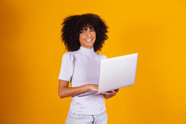 Lavoro a distanza! Ritratto di giovane donna afro eccitata che tiene il computer portatile isolato su sfondo giallo. Copyspace per il testo.