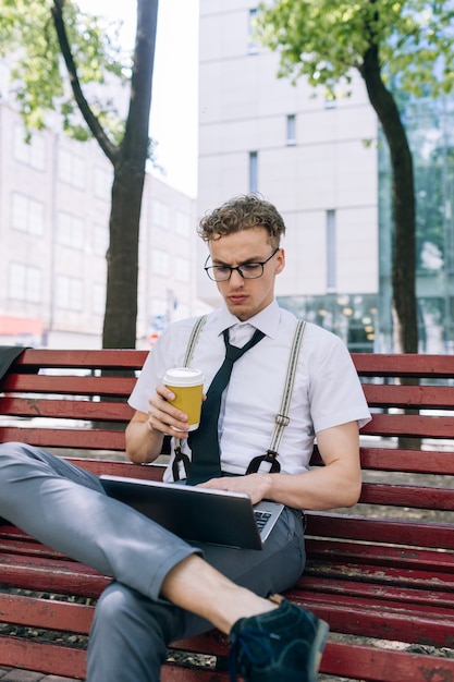 Lavoro a distanza. soluzioni tecnologiche online wifi internet. uomo d'affari che utilizza laptop sulla panchina nel parco all'aperto all'aria aperta.