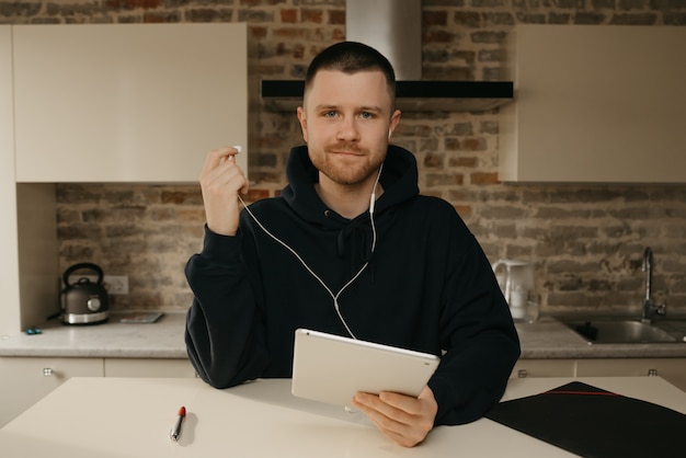 Lavoro a distanza. Un uomo con la barba che lavora da remoto sul suo tablet. Un uomo d'affari ha messo in pausa una telefonata con i suoi colleghi su un business da una videoconferenza.