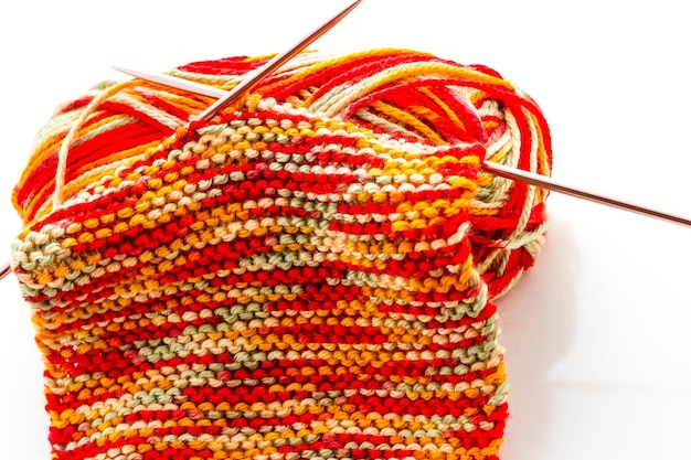 Lavoro a maglia con filati multicolori con toni arancioni, rossi e gialli.
