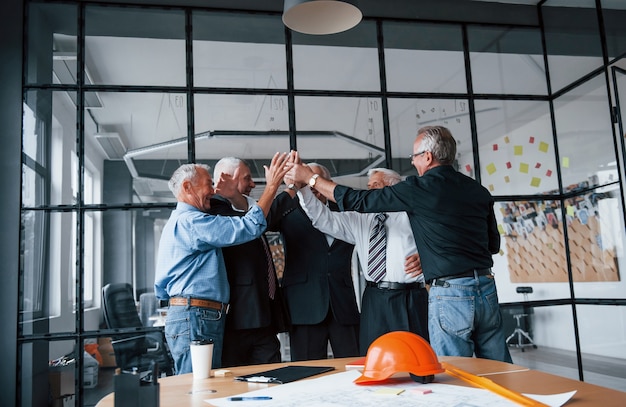 Lavoro ben fatto, si dà il cinque a vicenda. Il team di anziani architetti d'affari si trova in ufficio insieme.